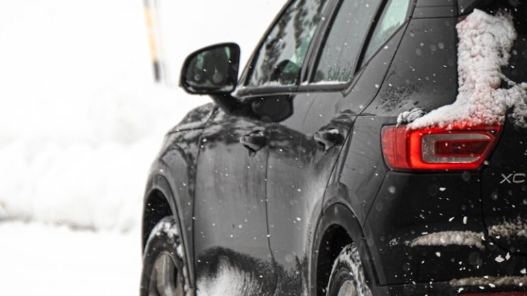 a black car driving down a snow covered road